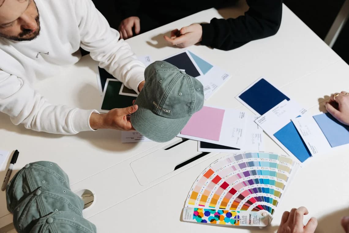 A Go Swag team member reviewing a branded cap against Pantone swatches