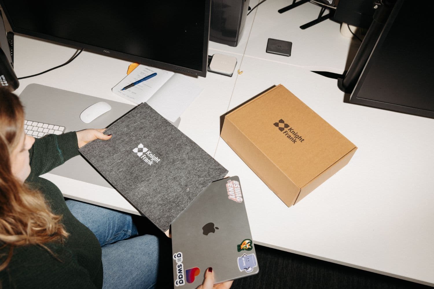 A new starter unpacking a Knight Frank welcome pack at their desk