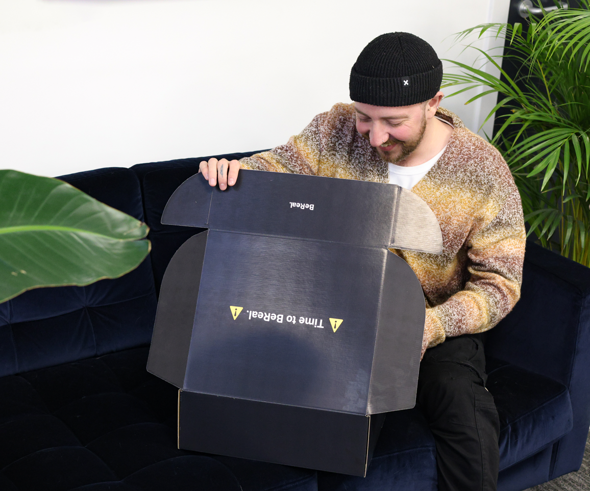 Photograph of a man excitedly opening a branded box
