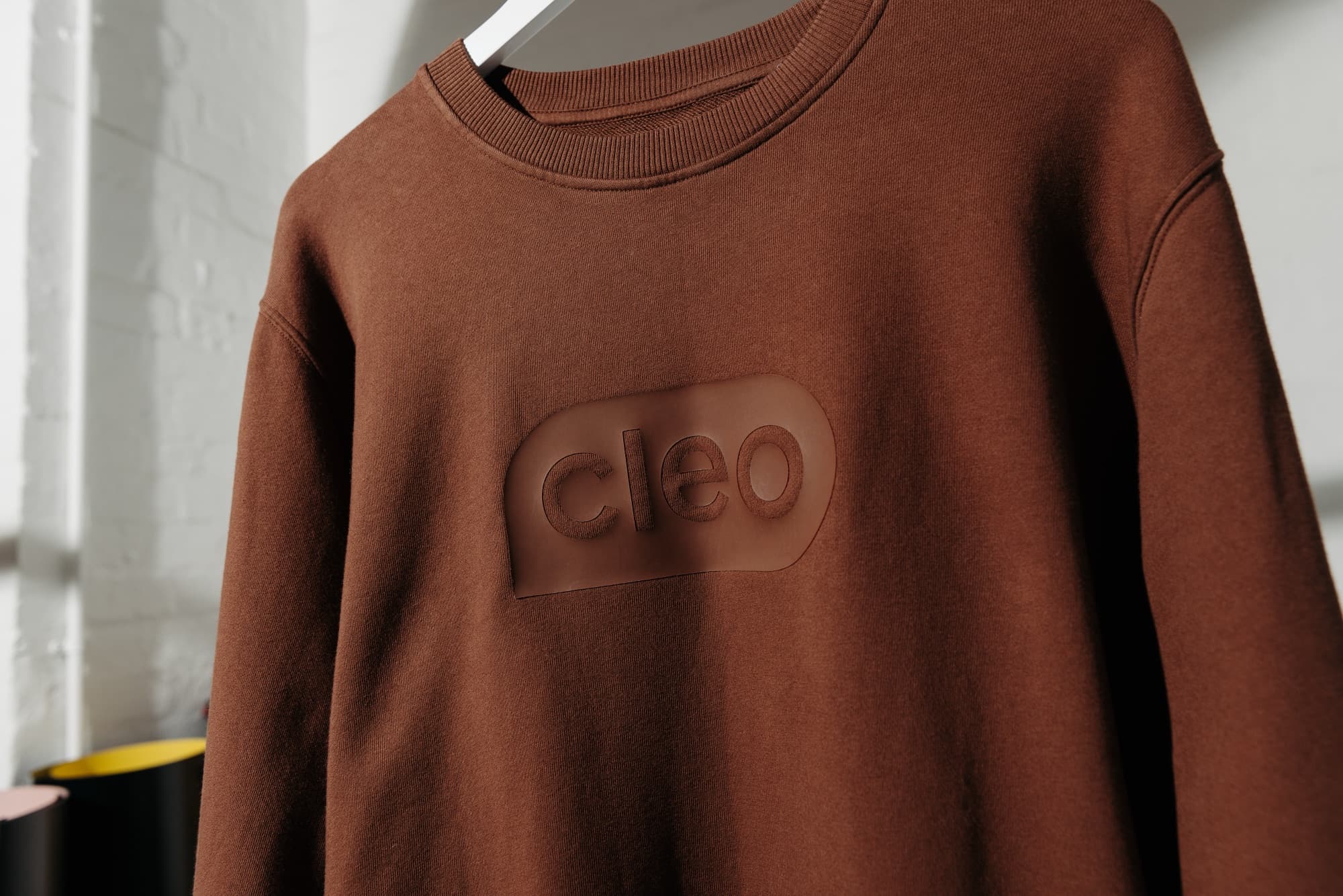 Embossed logo on a brown branded Cleo sweatshirt