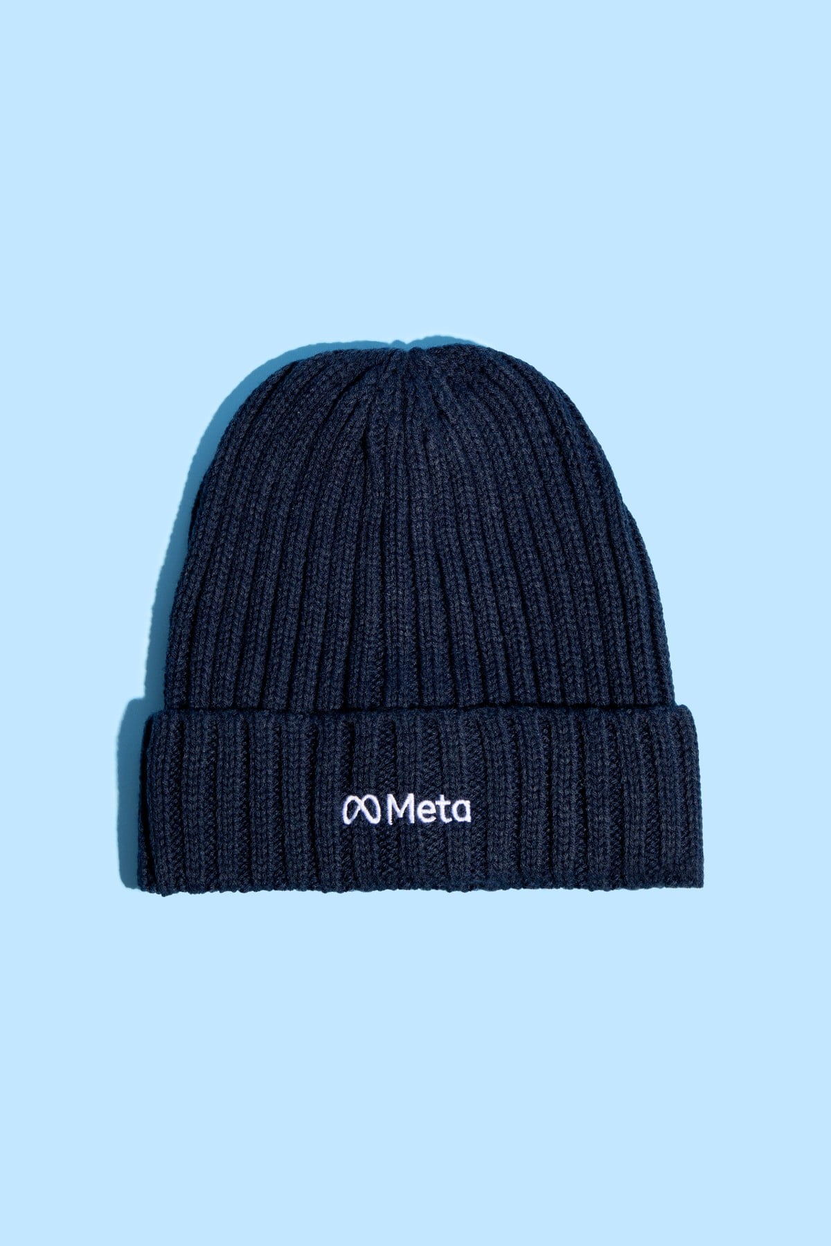 Detail of the embroidered Meta logo on a navy knitted beanie.