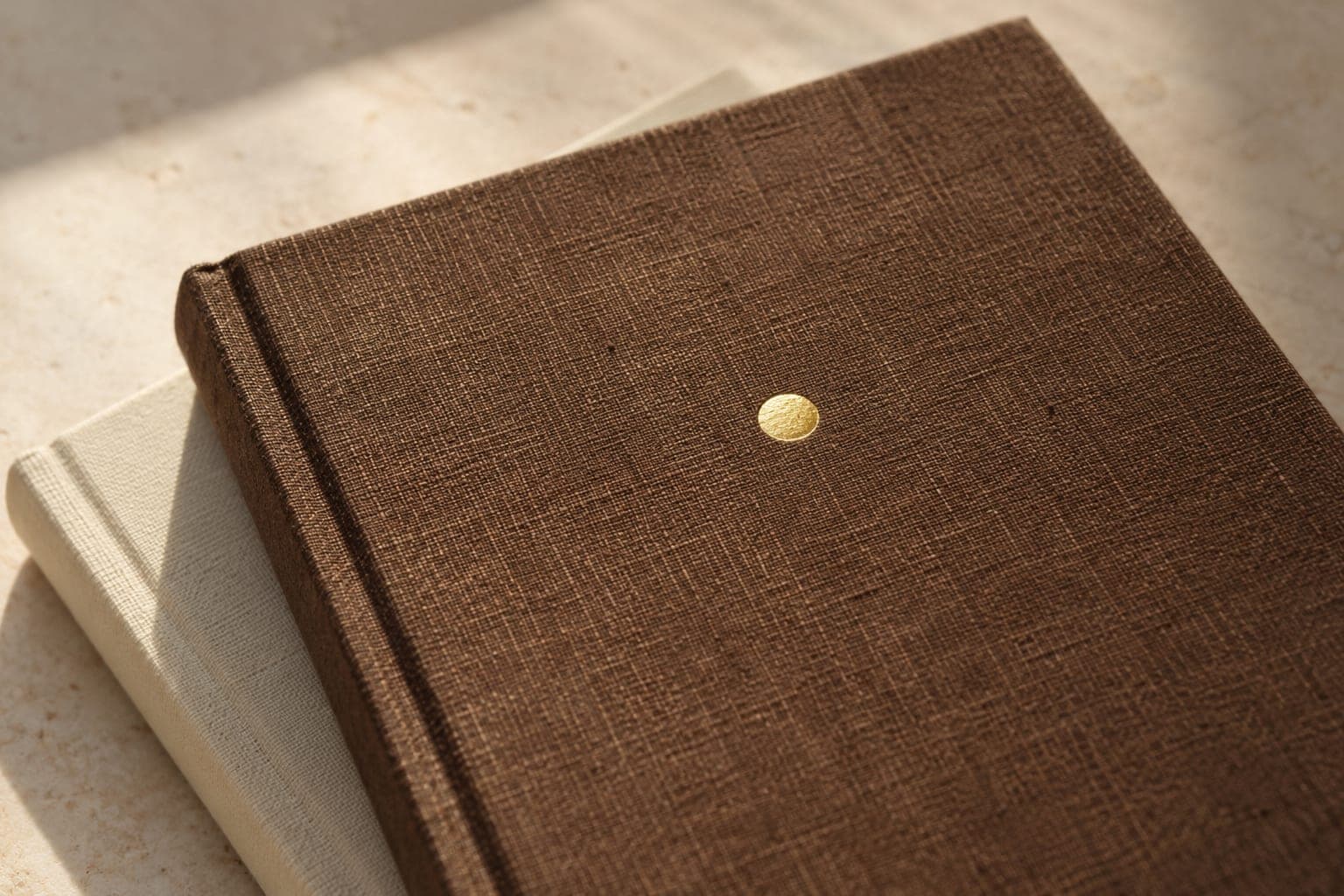 A gold foil circle stamped on a brown linen notebook cover