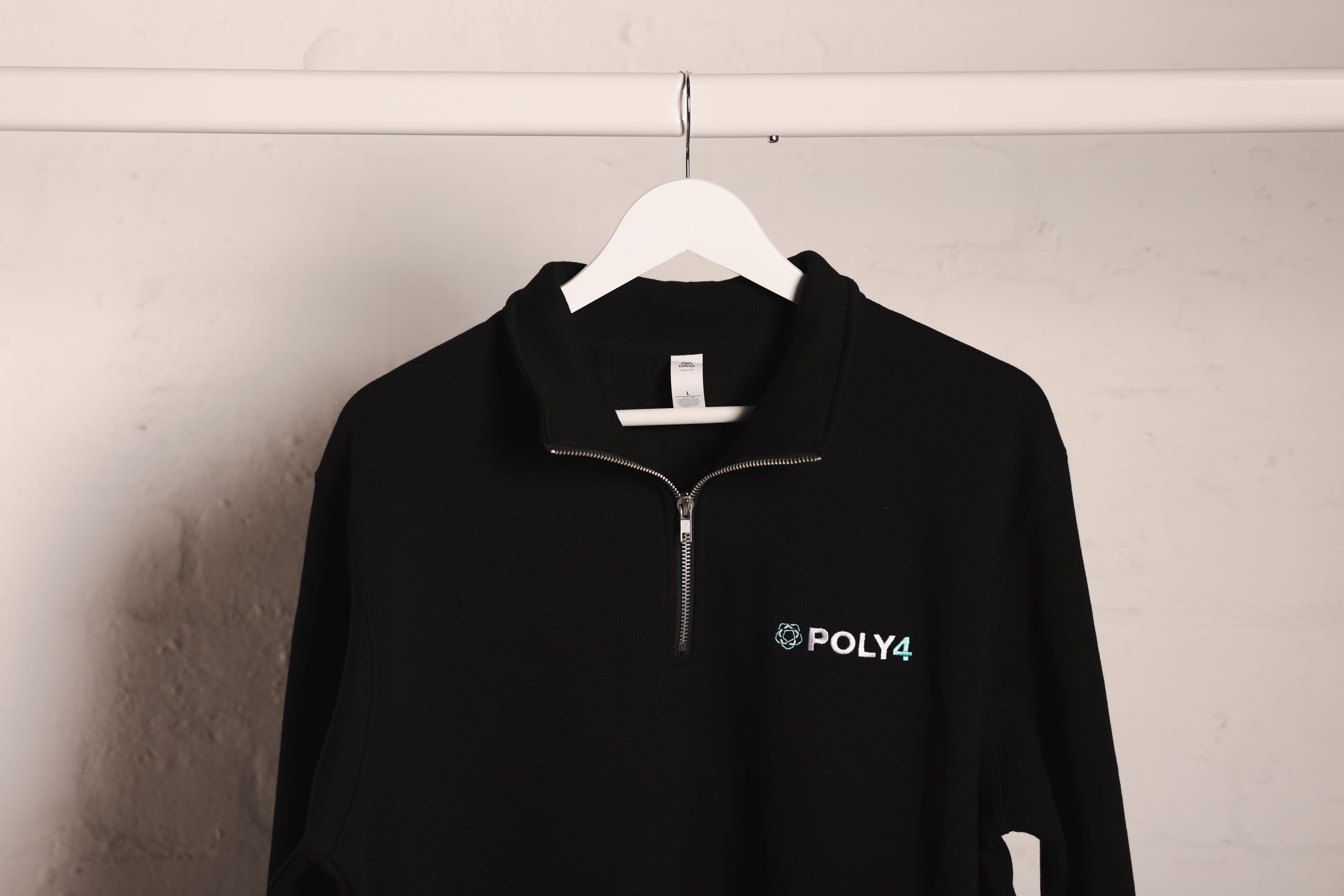 A black quarter-zip sweatshirt with POLY4 chest embroidery on a white rail