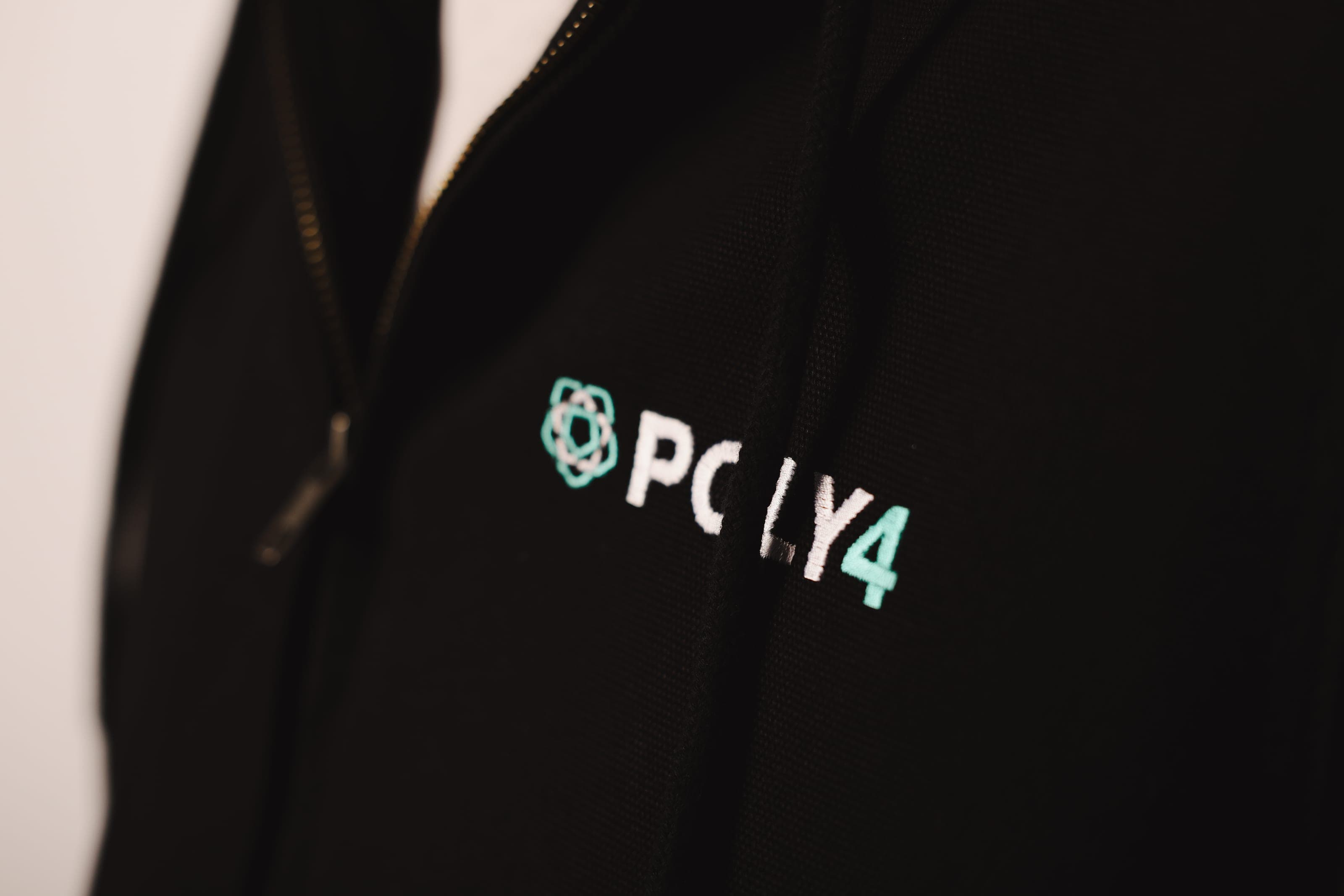Close-up of POLY4 logo embroidery on a black jacket
