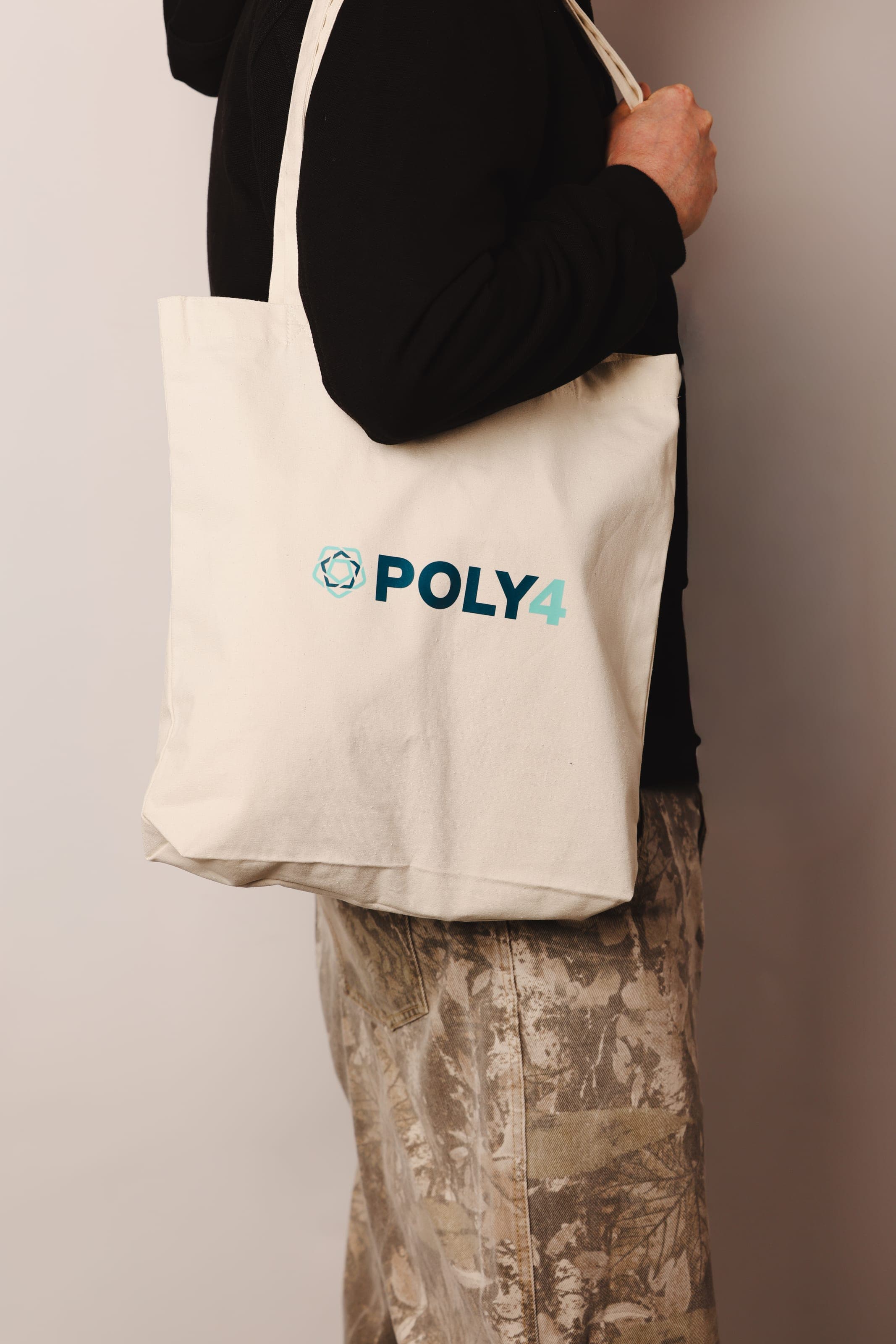 Natural canvas tote with a POLY4 logo carried on the shoulder