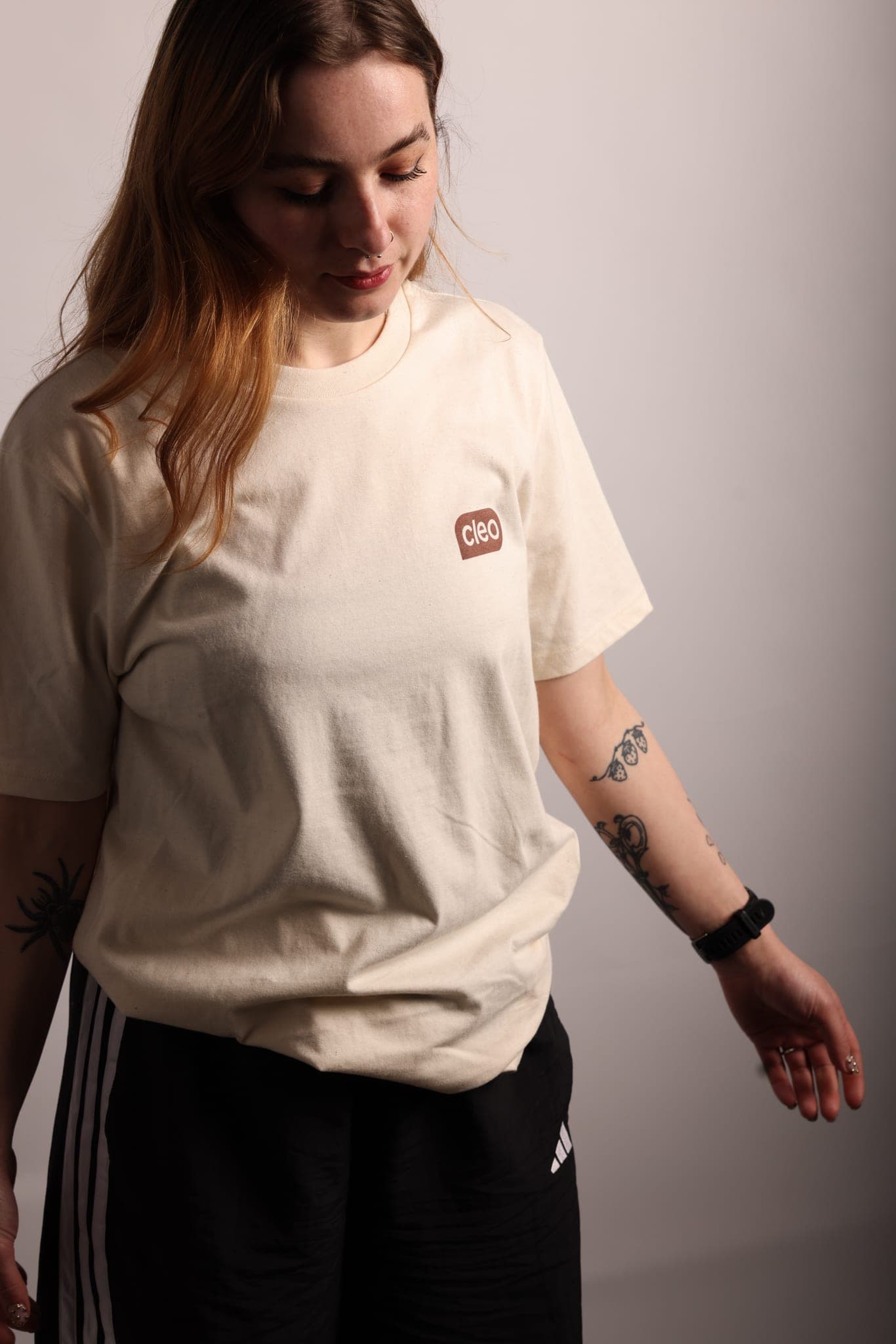 A woman with long auburn hair wearing a cream Cleo T-shirt
