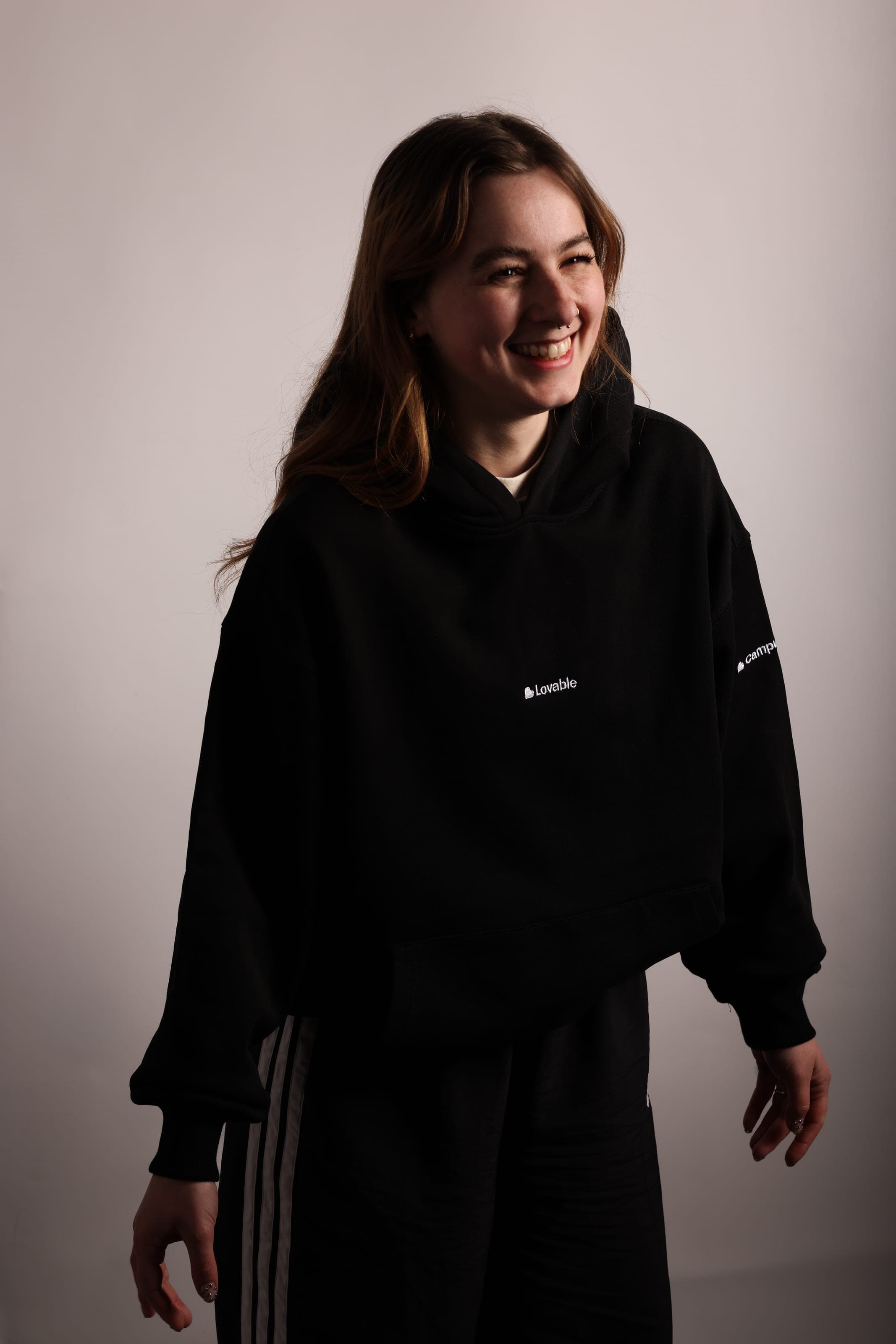 A smiling woman with long auburn hair in a black Lovable hoodie