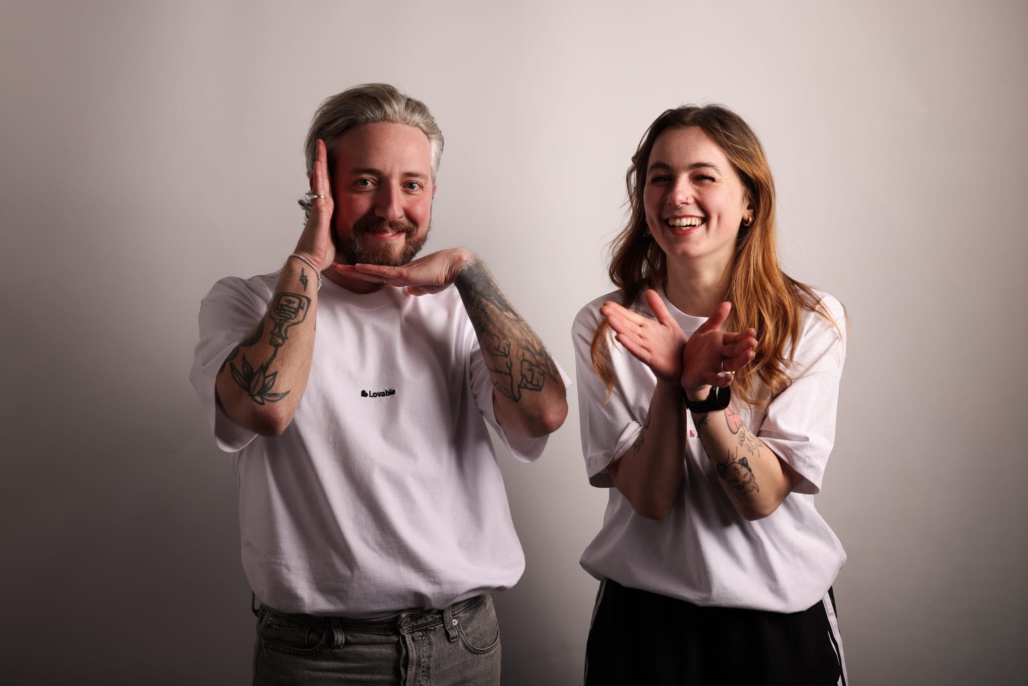A man frames his face with his hands while a laughing woman stands beside him, both in Lovable clothing