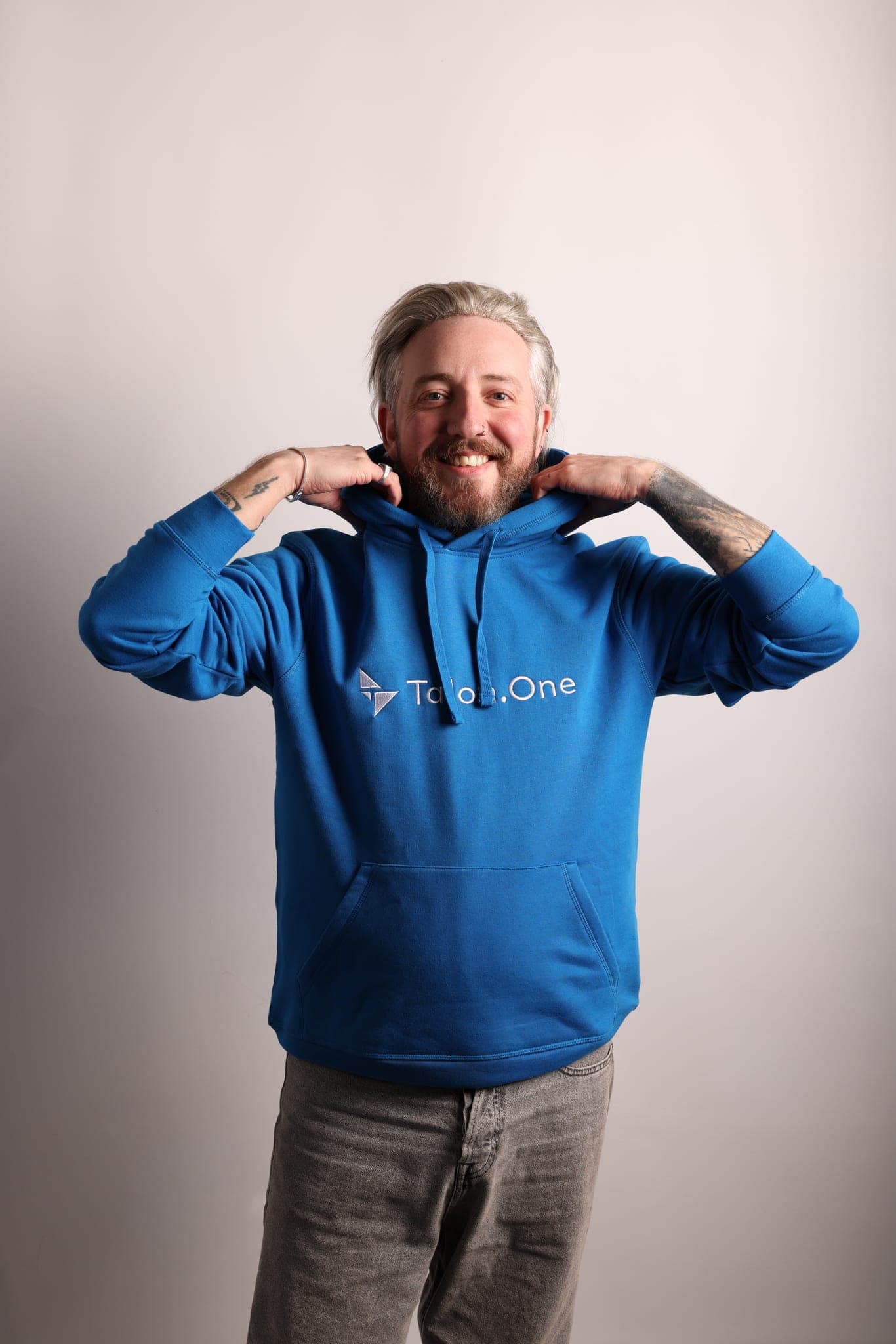 A grinning grey-haired man holds the hood of a bright blue Talon.One hoodie