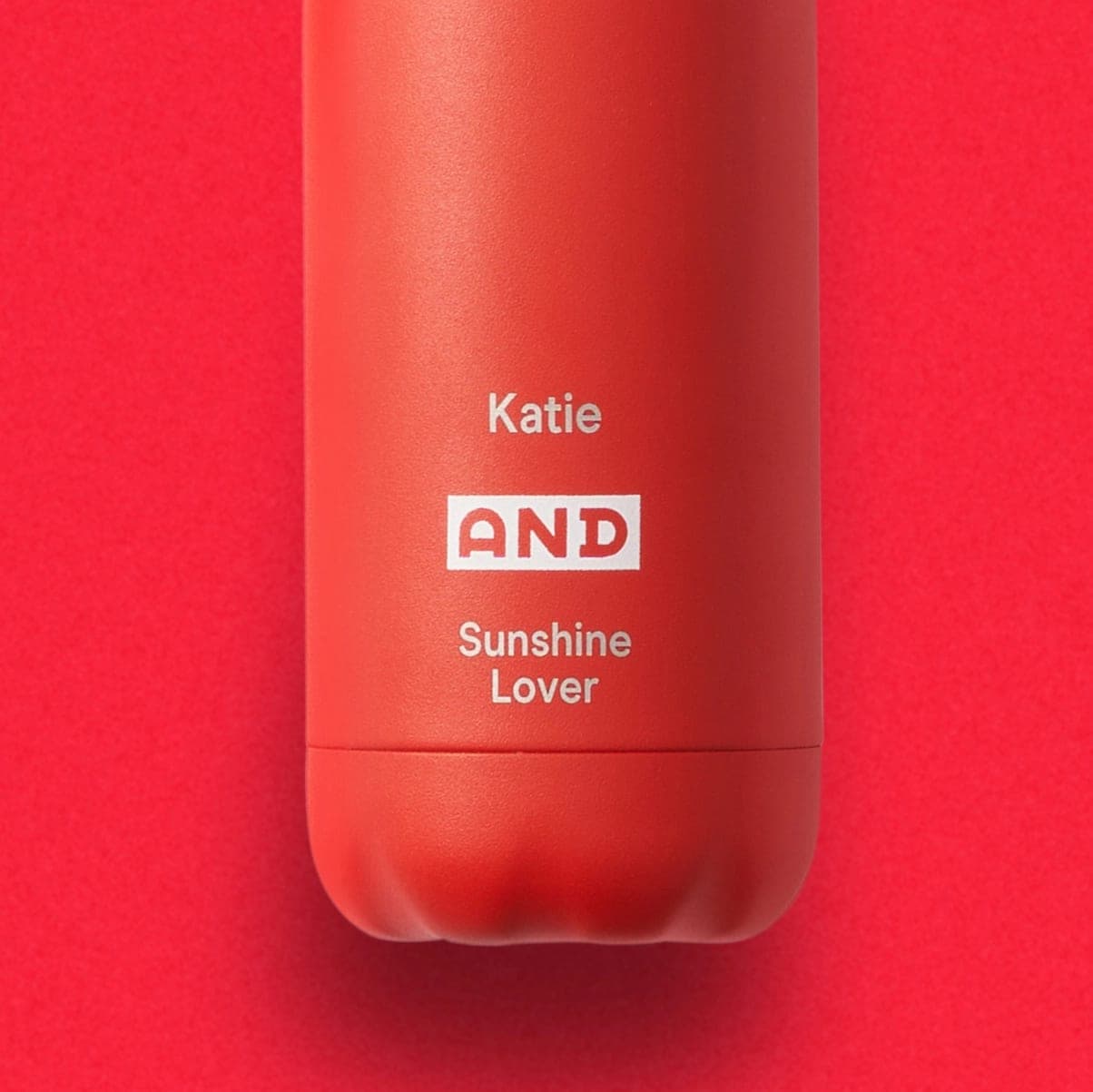 Close-up of a red AND Digital bottle printed in white with a first name, the AND logo and the title “Sunshine Lover”