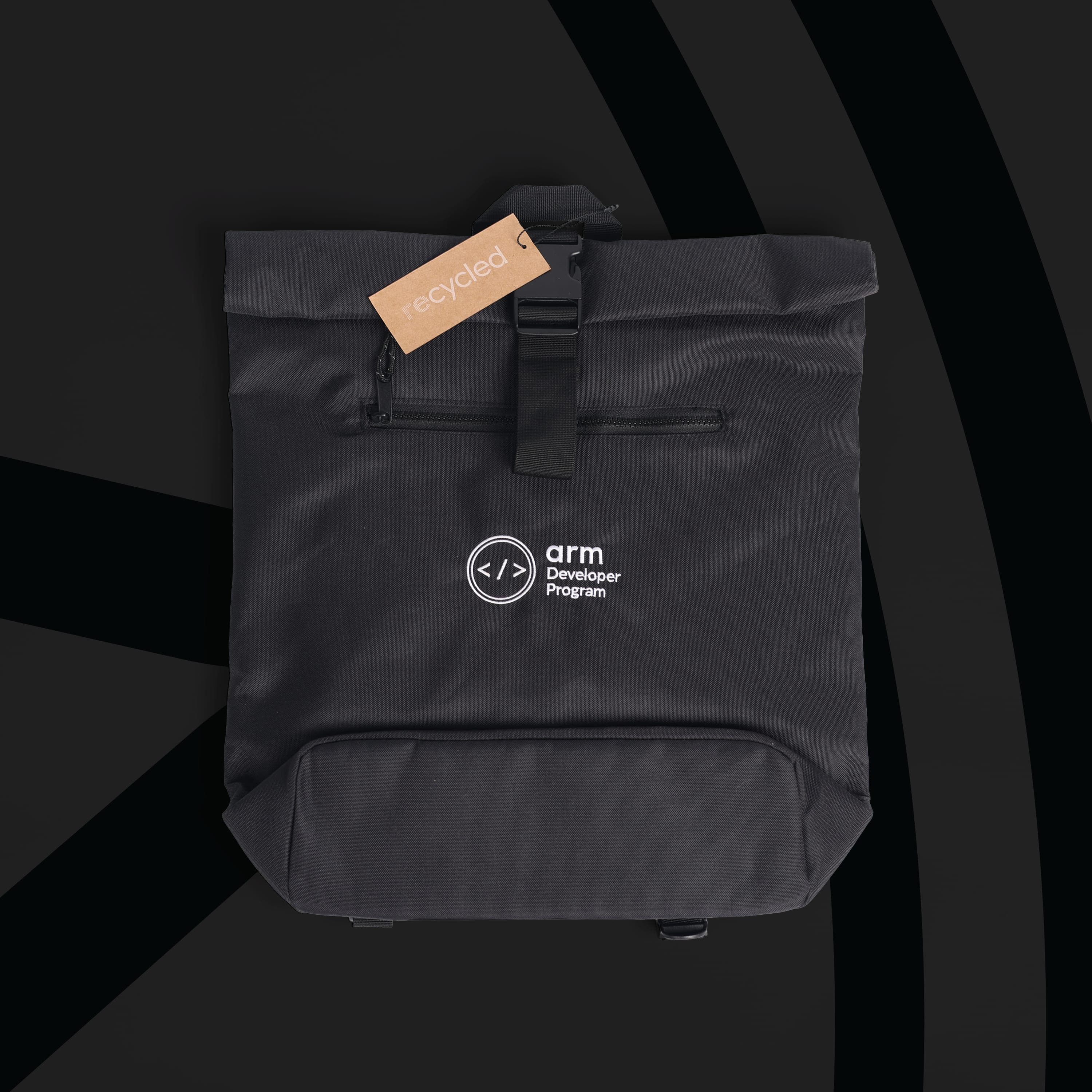 A black roll-top backpack with a front zip pocket and buckle strap, printed with the Arm Developer Program logo