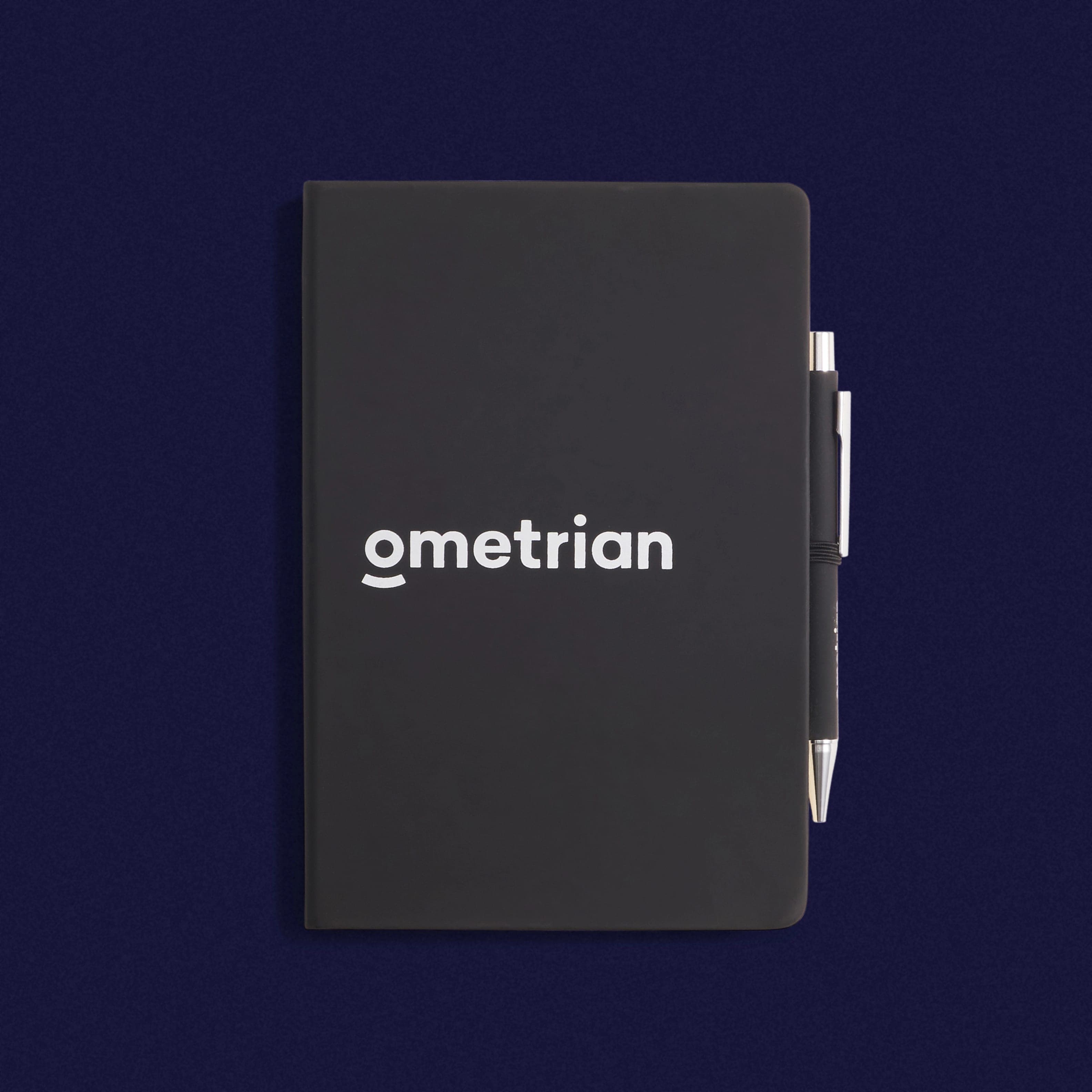 A black notebook printed “ometrian” in white, with a black pen in a side loop