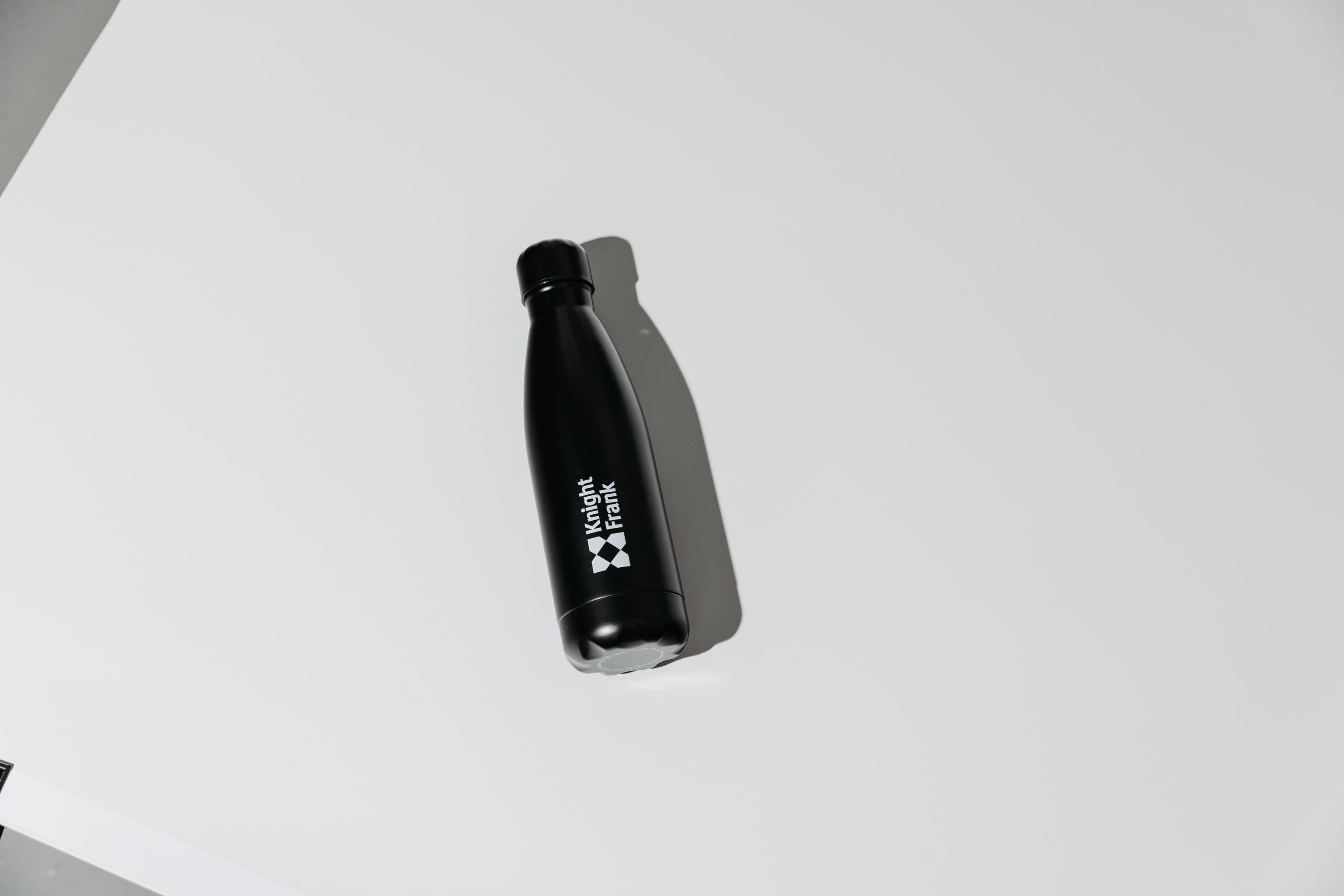 A black Knight Frank bottle lying on a white surface