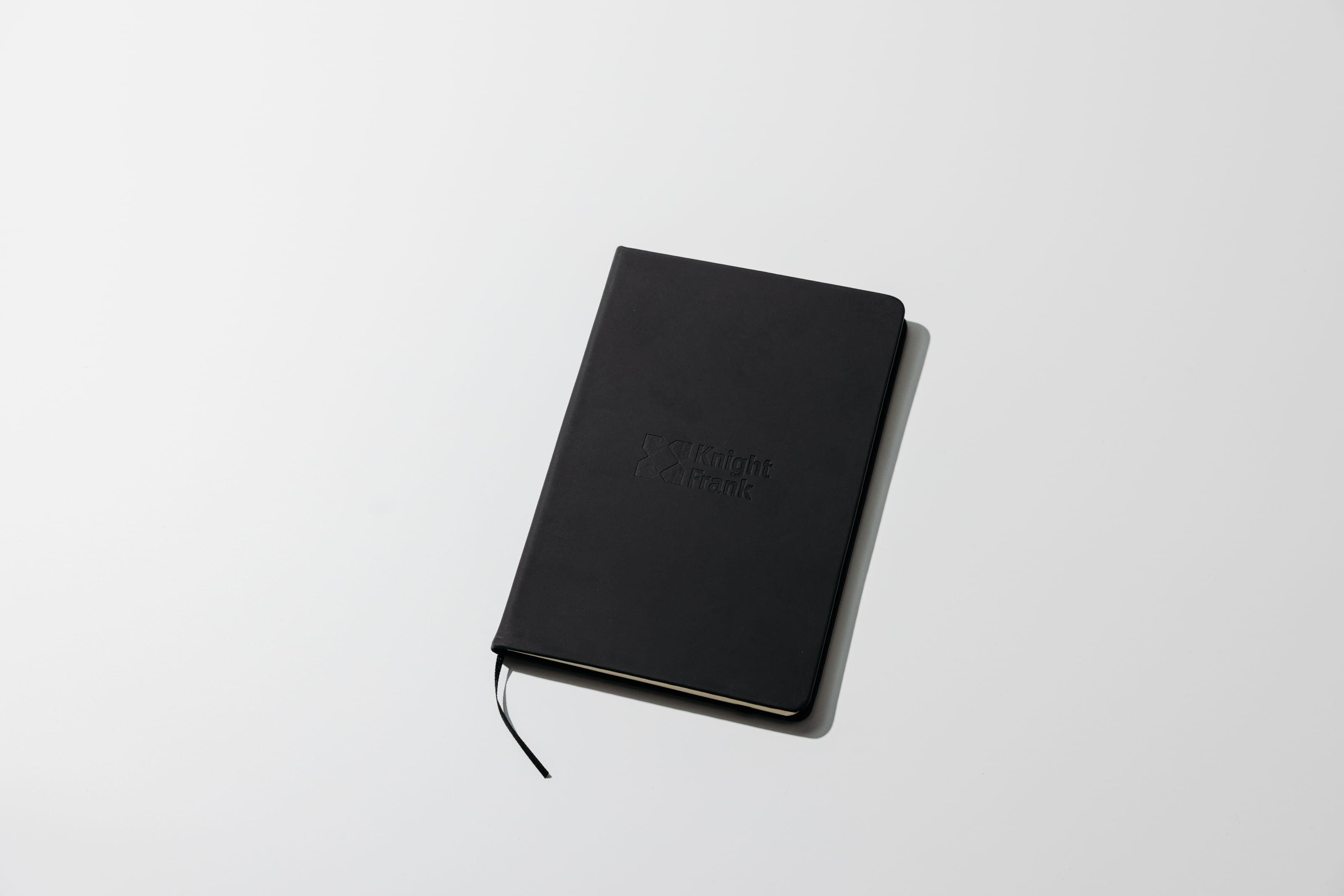 Black notebook with a tonal debossed Knight Frank logo on a white surface