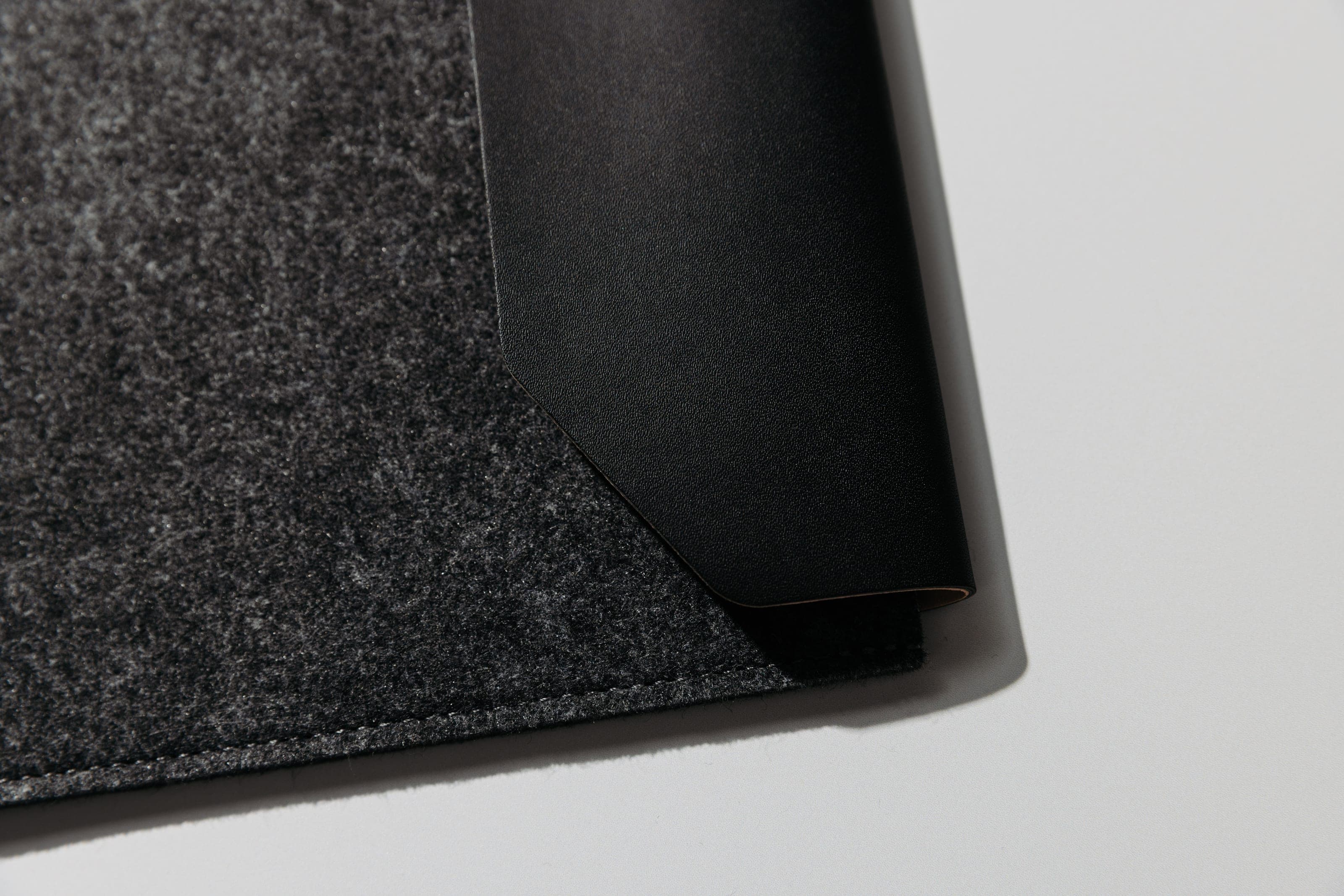 Close-up of a grey felt sleeve corner with a black flap and stitching