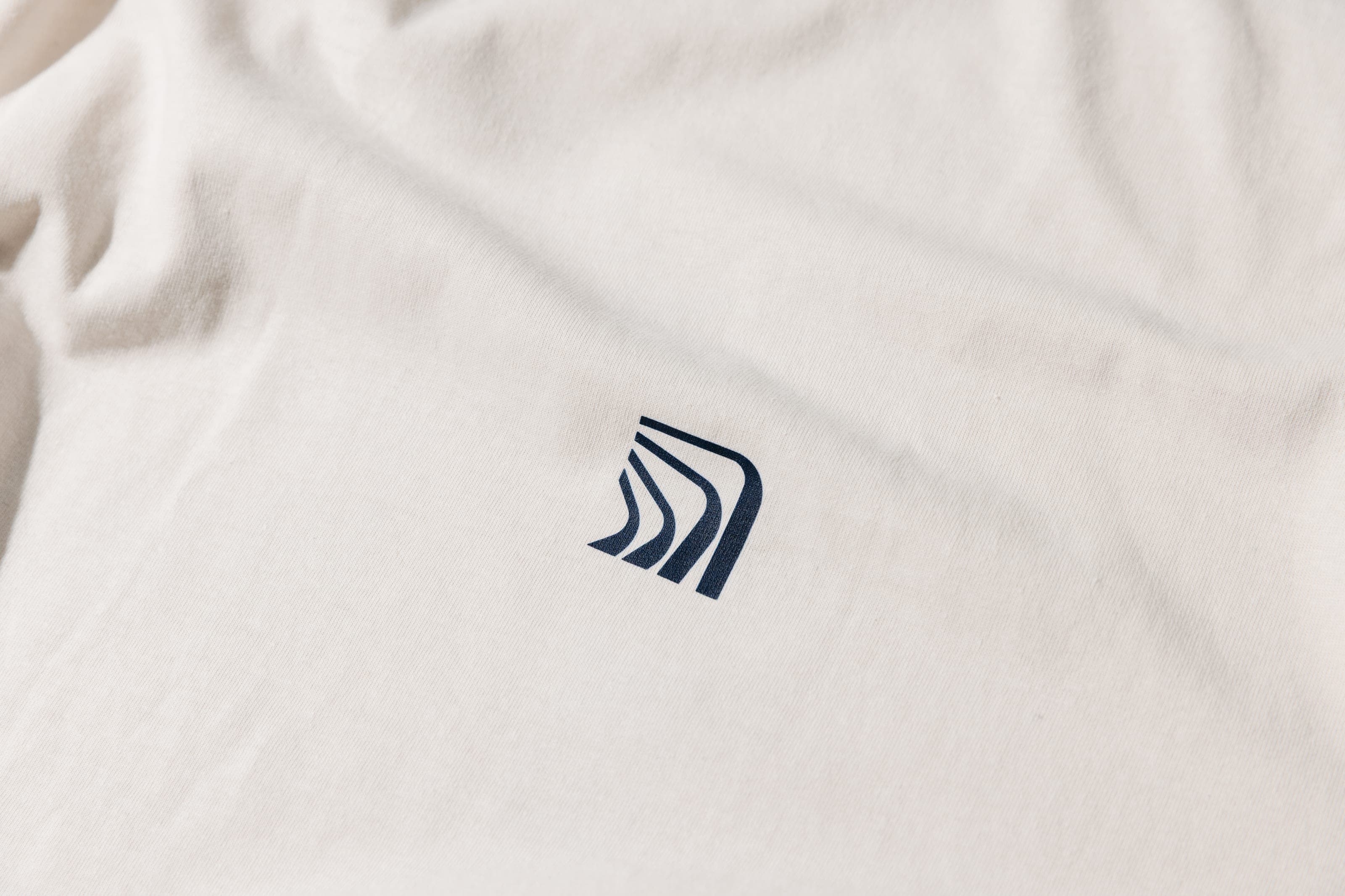 Small navy Exclaimer icon printed on a cream cotton T-shirt