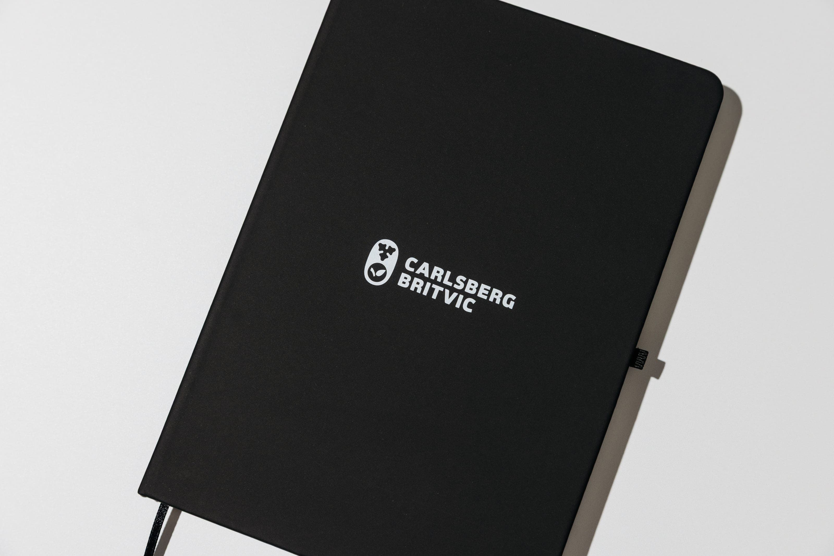 Close crop of a black notebook cover with a white Carlsberg Britvic logo