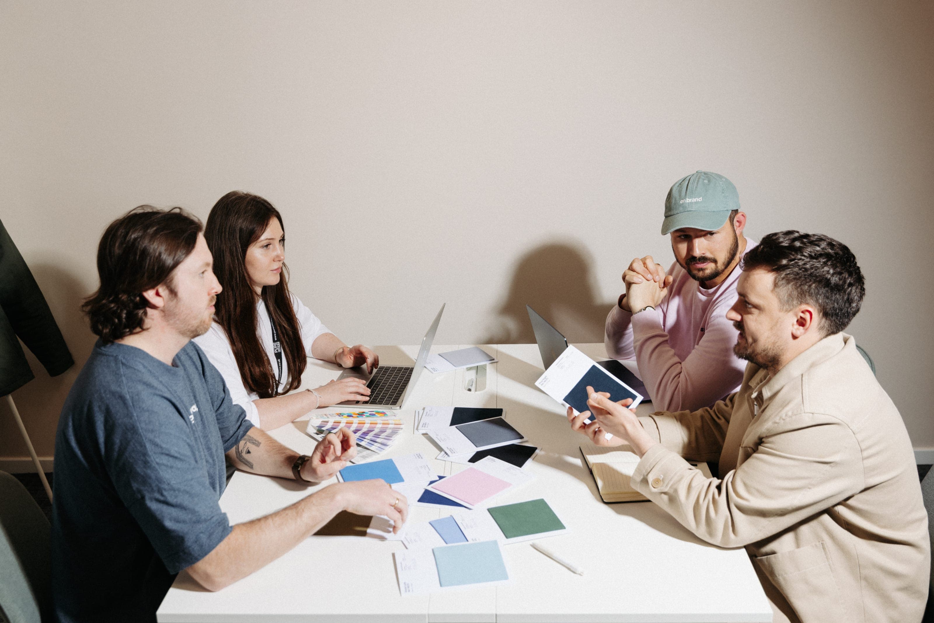 Four colleagues around a white table of colour swatches and laptops as one holds up a navy swatch