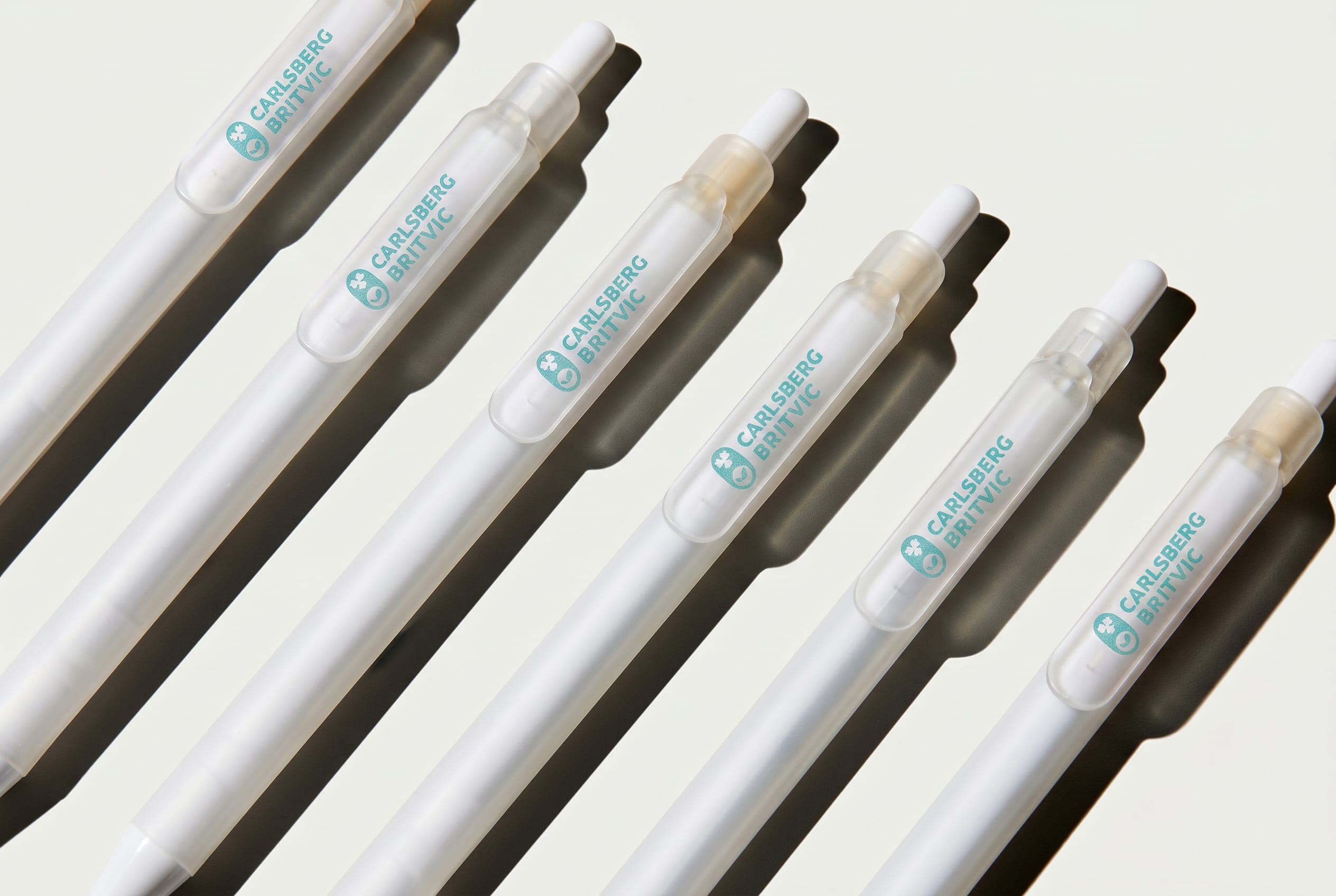 White pens in diagonal rows, each frosted clip printed with the teal Carlsberg Britvic logo